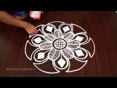 a person is drawing on the floor with white chalk and glue to make it look like an intricate flower