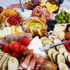 an assortment of cheeses, fruits and meats on a platter