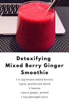 a smoothie in a glass next to a laptop on a table with the text detoxifying mixed berry ginger smoothie