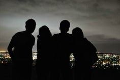 three people standing next to each other in front of a cityscape at night