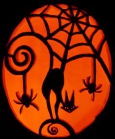 a carved pumpkin with an image of cats and spider webs on it's face