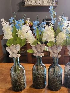 three glass vases with flowers in them and elephants on the top are sitting on a table