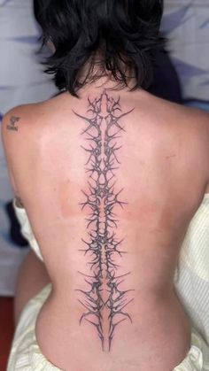 the back of a woman's neck with barbed wire on her upper and lower back