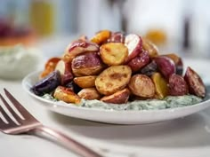 a white plate topped with potato salad next to a fork