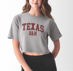 Score a touchdown in style with our Women's Texas A&M Varsity Crop Top, a fashionable nod to the timeless allure of varsity-inspired fashion. Tailored from premium 100% cotton, this tee guarantees comfort as you showcase your Aggie pride during thrilling game days at Kyle Field or while exploring the bustling streets of College Station. With its classic varsity design, this crop top adds a touch of retro sophistication to your ensemble, making it the perfect choice for tailgates, pep rallies, or Fitted Athleisure Tops For College, Sporty Tops For Campus During Sports Season, Collegiate Short Sleeve Tops For Campus, Varsity Cotton Tops With University Logo, Fitted Collegiate Top With Letter Print, Fitted Collegiate Letter Print Top, Cotton Varsity Top With University Logo, Fitted Collegiate Style Top With Letter Print, Varsity Short Sleeve Tops For Fall