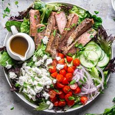 a salad with meat, tomatoes, cucumbers, lettuce and dressing