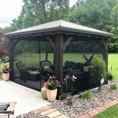 a gazebo in the middle of a yard with chairs and plants on it,