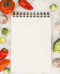 an open notebook surrounded by various vegetables