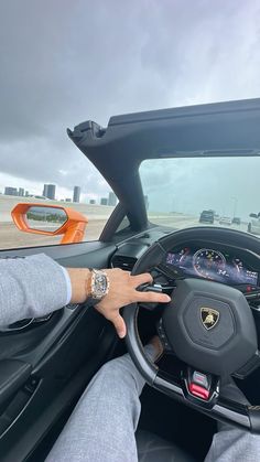 a man driving a car with his hand on the steering wheel while wearing a watch