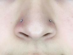 a close up of a person's nose and nose piercings