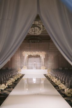 the aisle is lined with white flowers and draped drapes for an elegant wedding ceremony