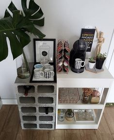 a shelf with coffee cups and mugs on it next to a potted plant