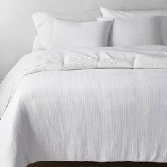 a bed with white sheets and pillows on it