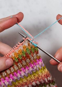 two hands are holding a knitting needle and crocheting the stitchs on it