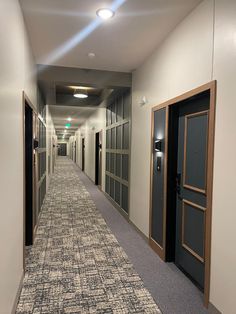 an empty hallway with doors and carpeted flooring