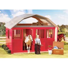 a man standing next to a horse inside of a red shed with the door open