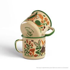 two coffee mugs are stacked on top of each other, one is decorated with birds and flowers