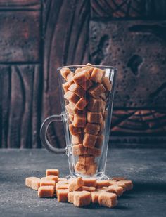 a glass cup filled with sugar cubes on top of a table