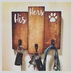 two wooden signs with keys hanging from them on a wall next to other key holders