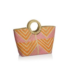 an orange and pink handbag with a circular handle on the front, sitting against a white background