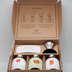 an open box containing three different types of coffees and two cups with labels on them