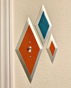 an orange and blue diamond shaped light switch cover on a white wall next to a door