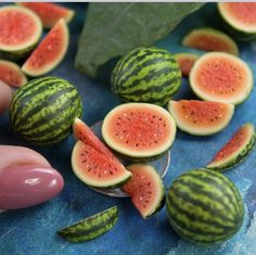 watermelon cut in half and placed on a blue surface with someone's finger