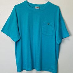 "Adult L Poly cotton blend 46\" chest 25\" length Awesome vintage cerulean blue 80s tee with a button pocket at the chest. Very soft and comfy, in great vintage condition with no noticeable flaws" Light Blue Tops With Pockets For Everyday, Vintage Crew Neck Top With Pockets, Vintage Washed Blue Tops With Pockets, Vintage Blue Shirt With Pockets, Blue Crew Neck T-shirt With Pockets, Casual Turquoise Crew Neck T-shirt, Blue T-shirt With Pockets And Short Sleeves, 90s Green Cotton T-shirt, Blue Cotton Throwback T-shirt