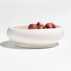 a white bowl filled with fruit sitting on top of a table