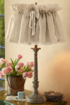 a lamp that is sitting on top of a table next to a vase with flowers