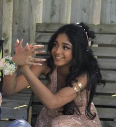 a woman sitting on top of a wooden bench holding her hands out to the side