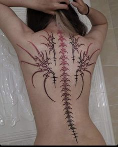 the back of a woman's body with an intricate tattoo design on her ribs