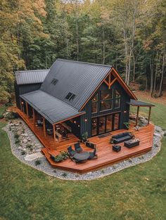 an aerial view of a house in the middle of a wooded area with patio furniture