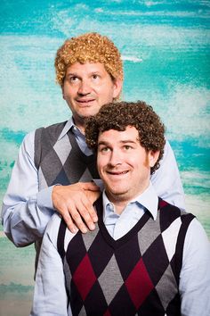 two men in sweaters and vests are posing for a photo with their arms around each other