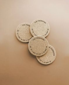 three coasters with the names of four famous authors on them, sitting in front of a brown background