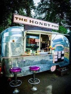 a food truck with two purple stools next to it and a sign that says the honey pot