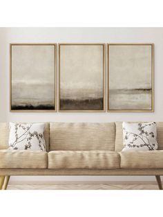 three paintings hanging on the wall above a couch in a room with white walls and beige furniture