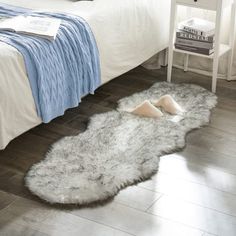 a bedroom with a white bed and gray rugs on the wooden floor next to it