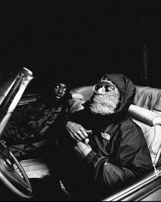 two people sitting in the back of a car at night, one with a beard