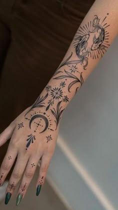 a woman's hand with tattoos on her left arm and the sun in the middle