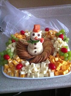 a platter filled with cheese, crackers and grapes next to a snowman