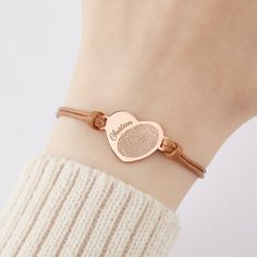 a woman wearing a bracelet with a fingerprint on it and a heart shaped charm