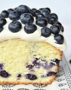 a blueberry cake with white frosting and fresh blueberries on top is sitting on a plate