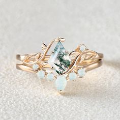 a white and green ring sitting on top of a white surface with opal stones