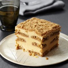 a piece of cake sitting on top of a white plate next to a glass of tea