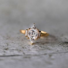 a close up of a ring with a diamond on the top and two baguettes in the middle