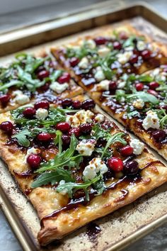 a pizza with cheese, cranberries and greens on it sitting on a tray