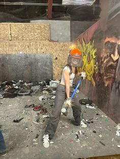 a person with a baseball bat standing in front of a wall covered in graffiti and trash