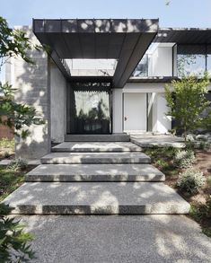 a modern house with concrete steps leading up to the front door