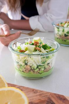 two people sitting at a table with some food in their hands and one person holding a fork